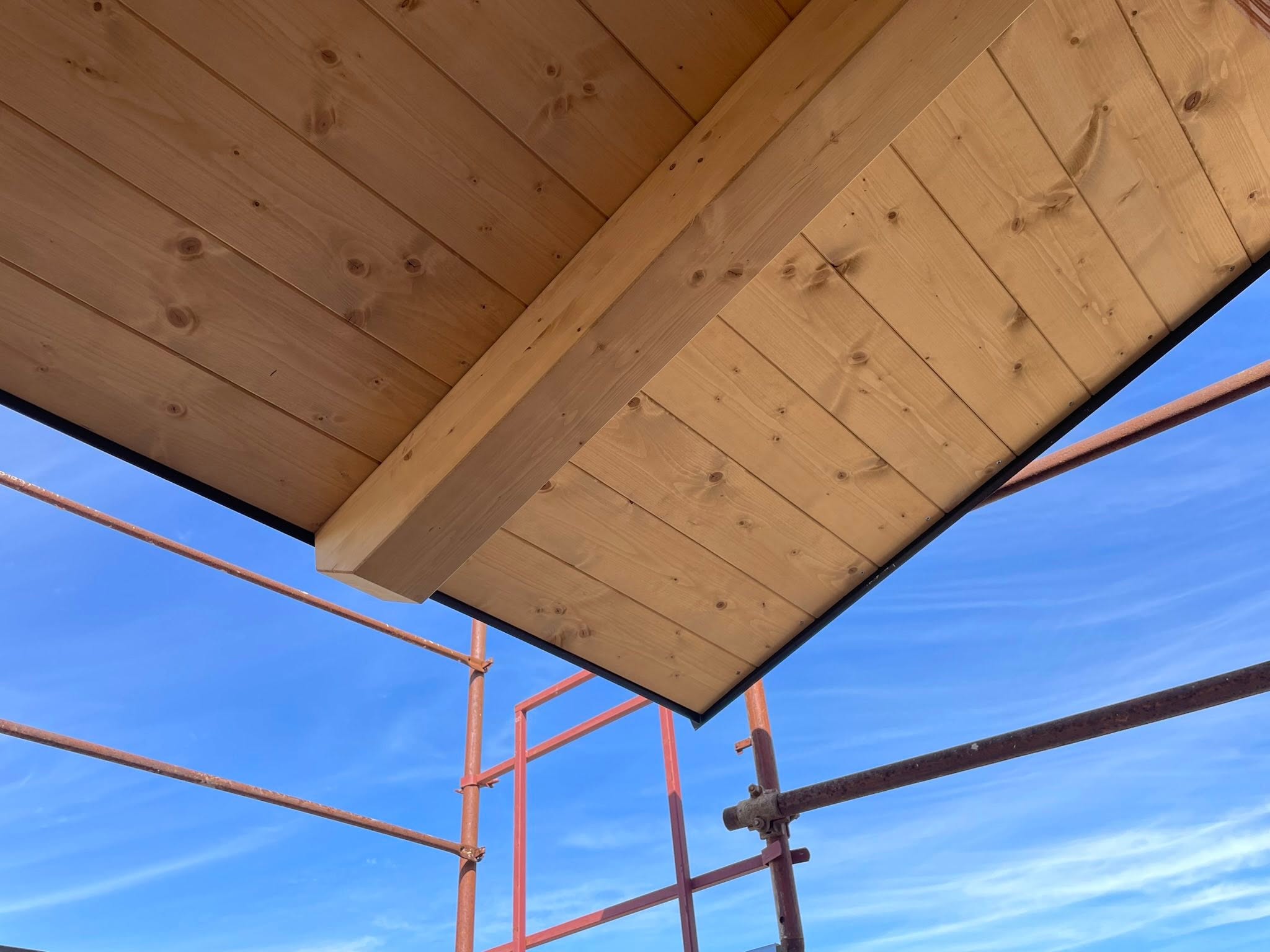 Vista dal basso della sporgenza del tetto in legno per la protezione della facciata di una villa in bioedilizia