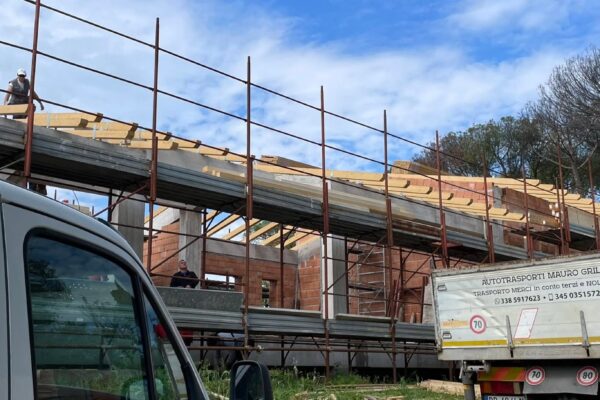 Operai edili impegnati nella posa dell'orditura secondaria del tetto in legno lamellare in un cantiere residenziale