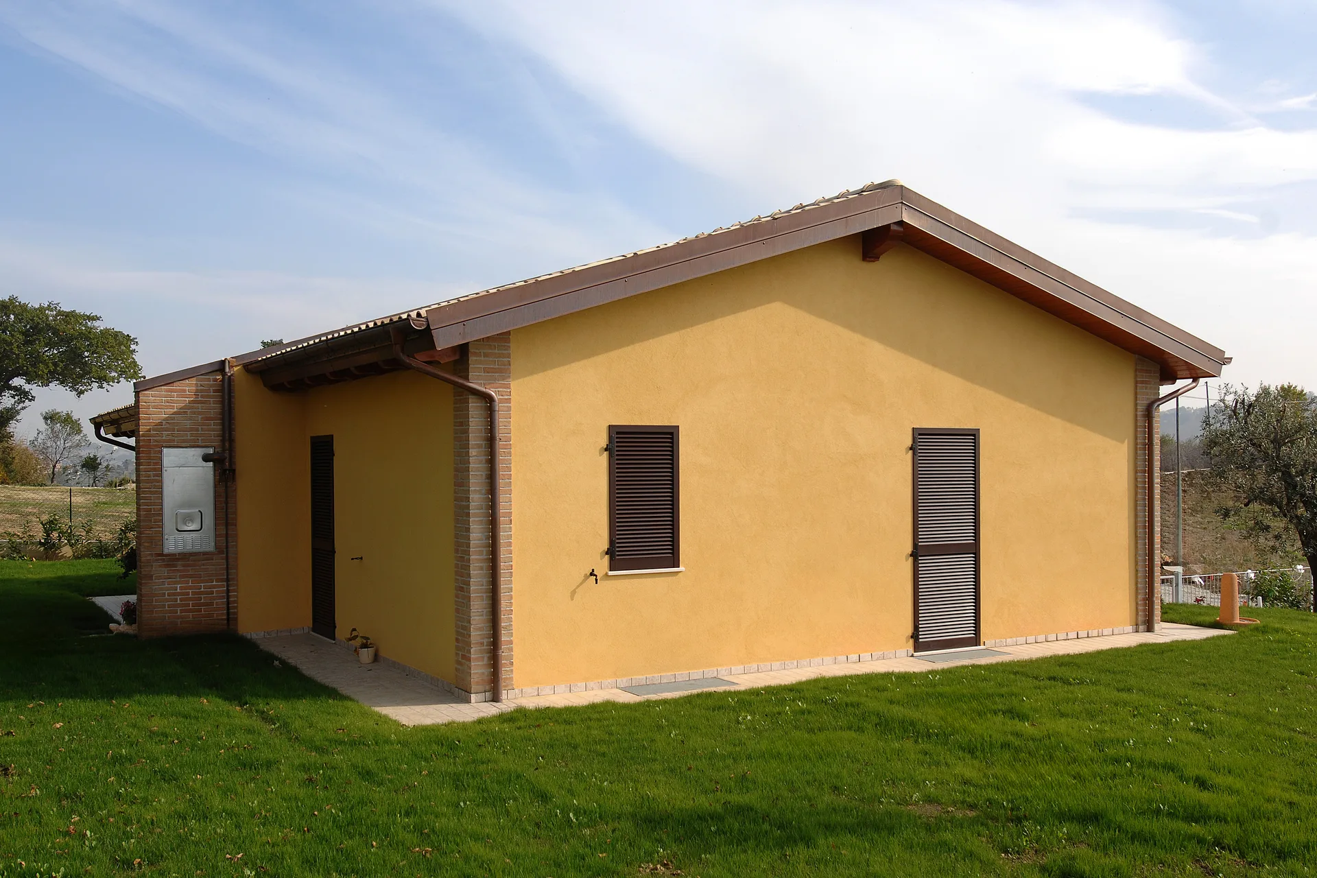 Facciata intonacata gialla e giardino di una moderna casa in legno prefabbricata a Rieti