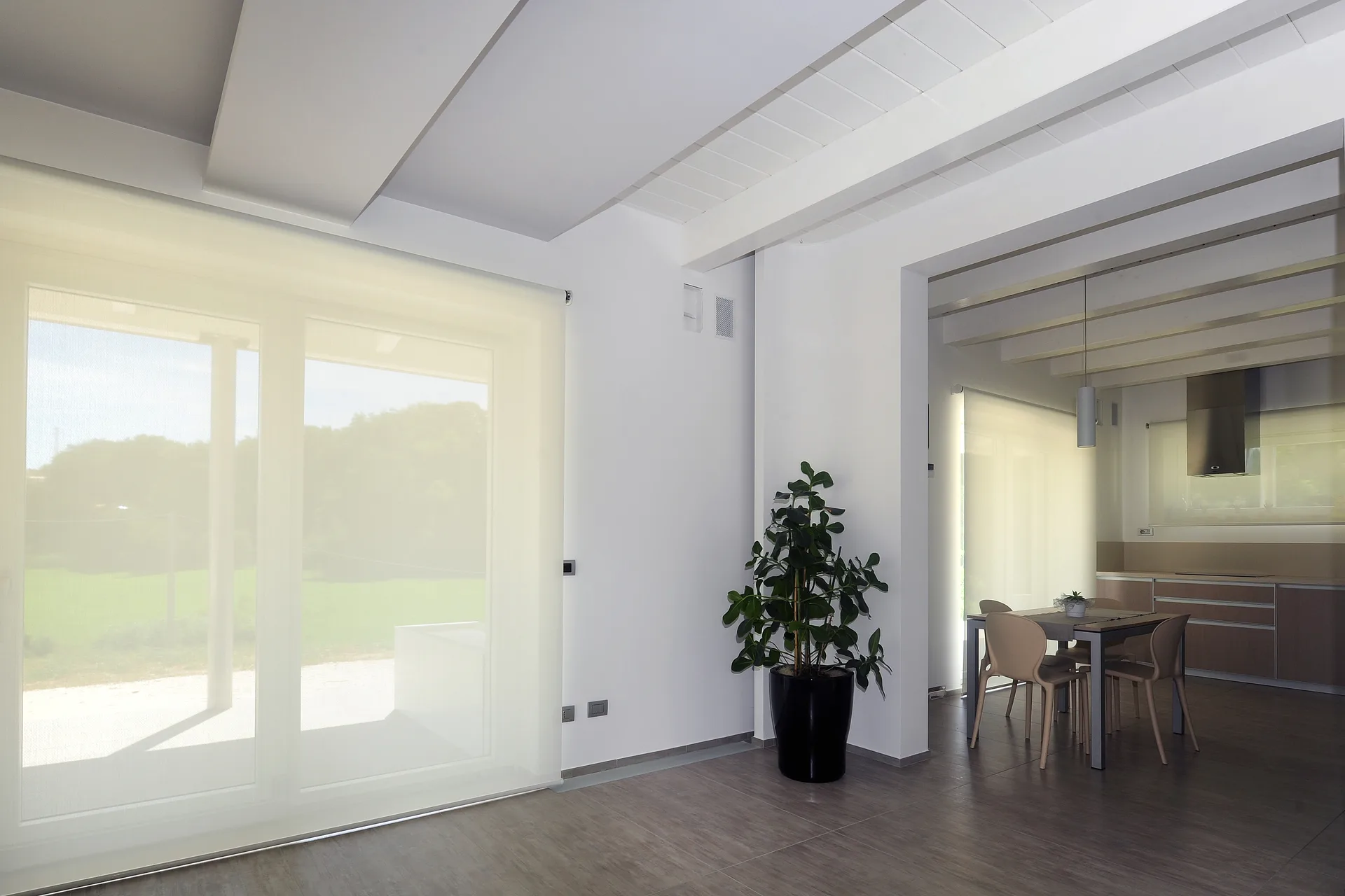 Interno open space con zona pranzo e grandi infissi scorrevoli e bocchette vmc di una casa passiva