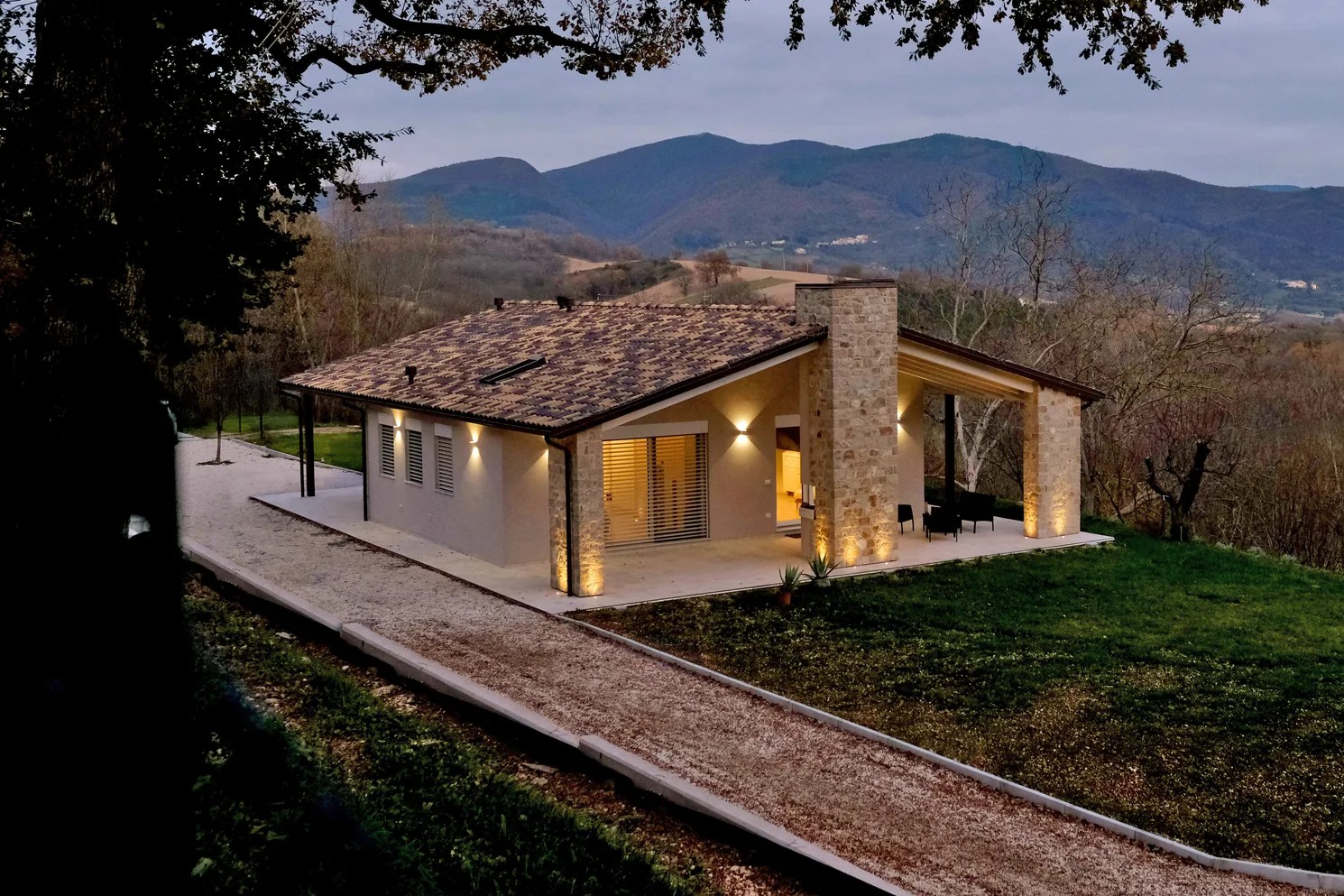 Casa in bioedilizia monofamiliare con porticato illuminato e tetto in legno lamellare, realizzata a Roma.